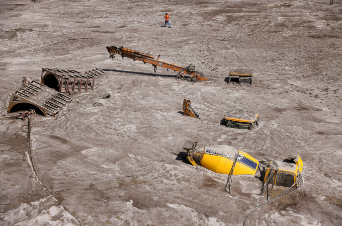 FILE PHOTO: Man walks past construction vehicles covered in debris caused by flash floods after a lake burst in Rangpo