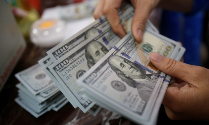 An employee of a bank counts US dollar notes at a branch in Hanoi